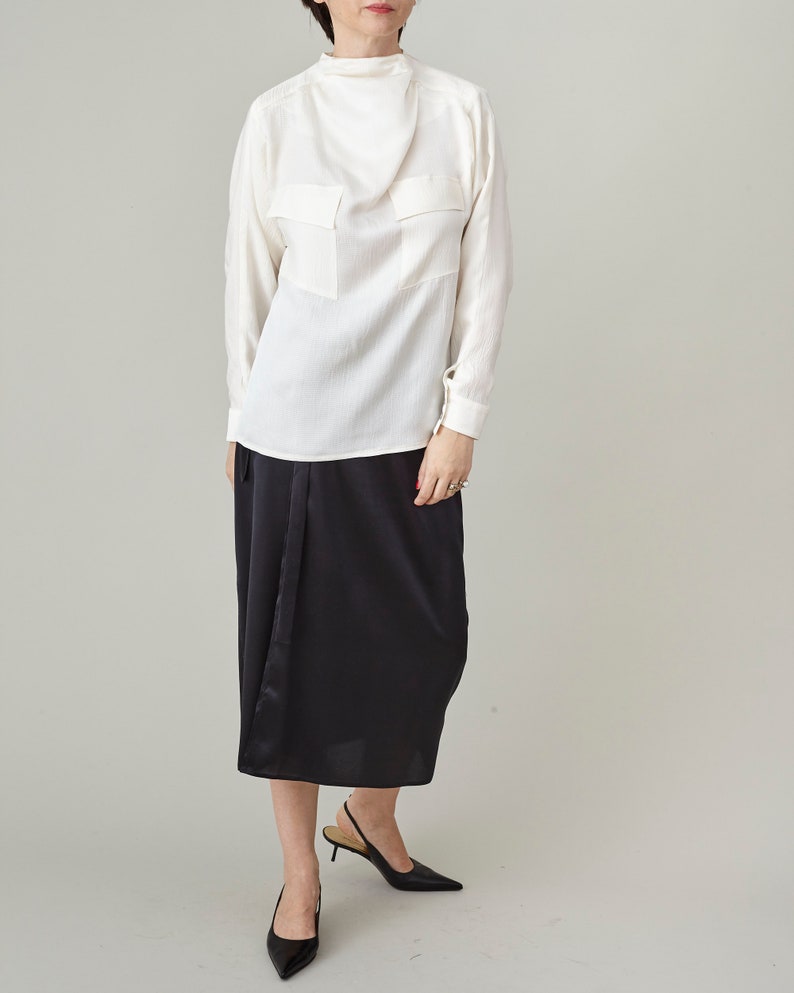 Person wearing a white blouse and black skirt on a plain background