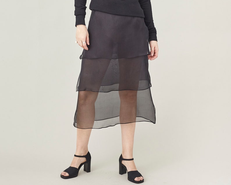 Person wearing a black sheer skirt in layers in a studio.