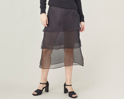 Person wearing a black sheer skirt in layers in a studio.
