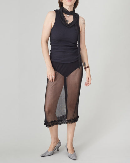 Person wearing a black sleeveless top and sheer black skirt on a gray background