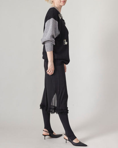 Person wearing a black outfit with a gray sleeve on a plain background