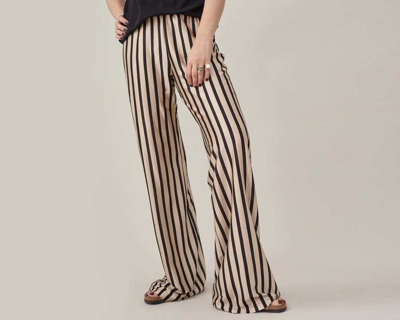 Front view of black and beige striped silk jersey flared pants with an elastic waist.