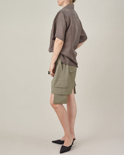 Back three-quarter view of the taupe silk short-sleeve blouse styled with khaki shorts.