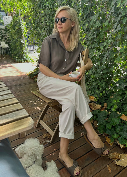 Taupe silk short-sleeve blouse styled casually outdoors with light trousers.