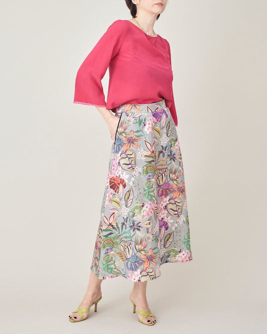 Woman wearing a pink top and floral skirt on a plain background