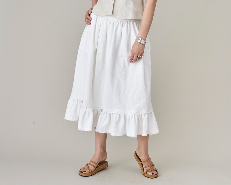 Person wearing a white skirt with ruffled bottom on a plain background