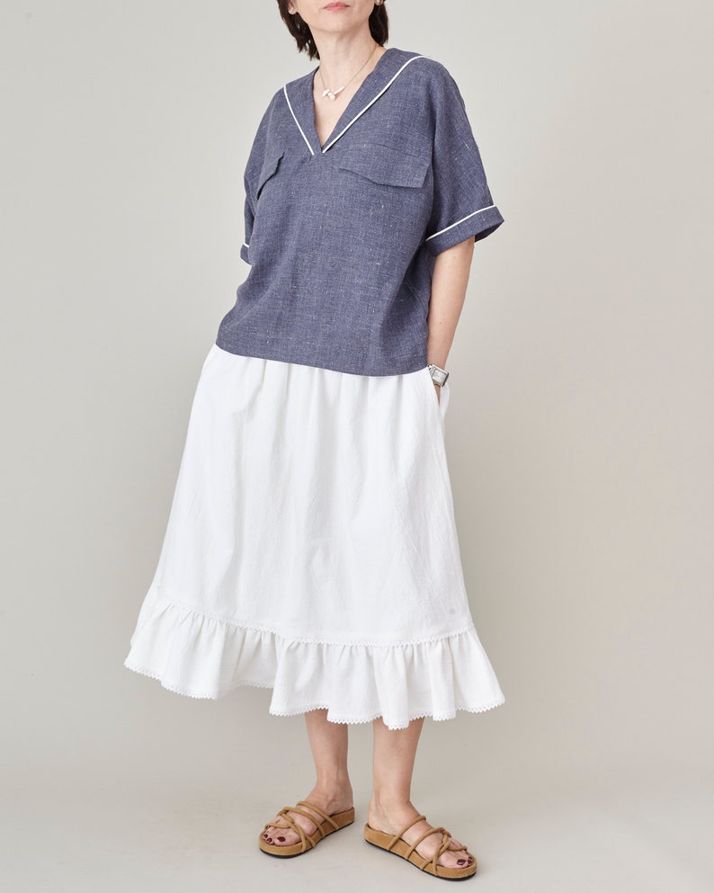 Woman wearing a sailor design blue top and white skirt on a plain background