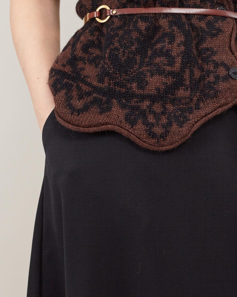 Brown patterned vest over a black skirt with side pockets