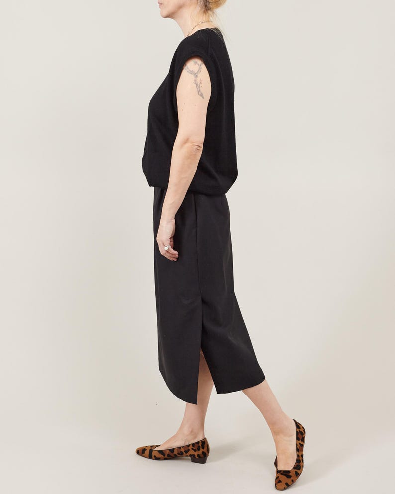 Person wearing a black sleeveless top and black wool midi skirt with a side slit, styled with leopard print shoes for an elegant natural-fiber daywear outfit