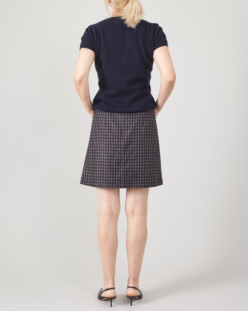Person wearing a navy top and plaid mini skirt on a white background