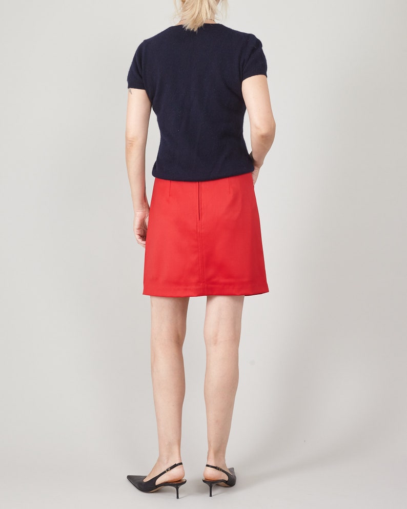 Person wearing a navy top and red skirt on a plain background