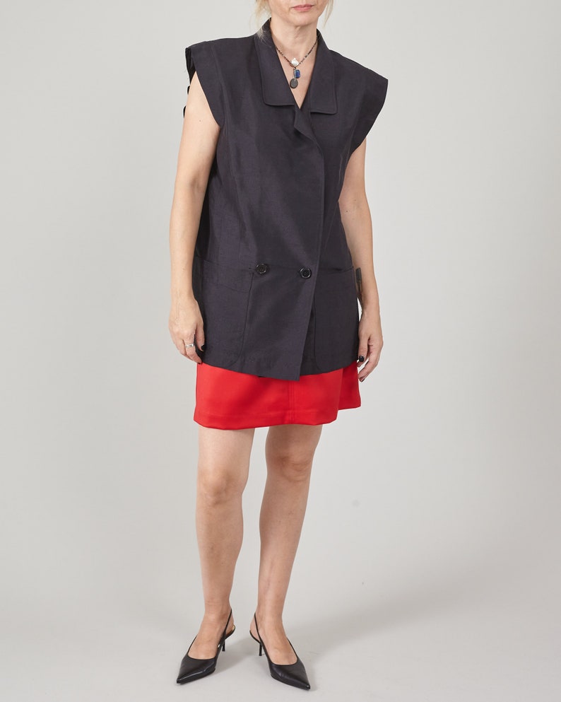 Woman wearing a black sleeveless blazer and red mini skirt in studio