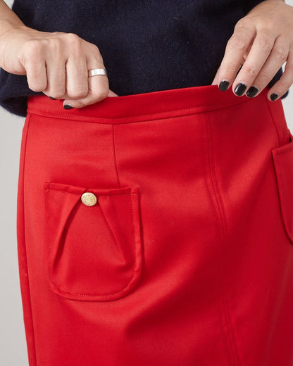 Red skirt with a gold button pocket worn by a person against a neutral background