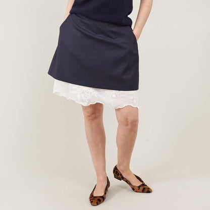 Navy skirt with white lace hem worn by a person on a plain background