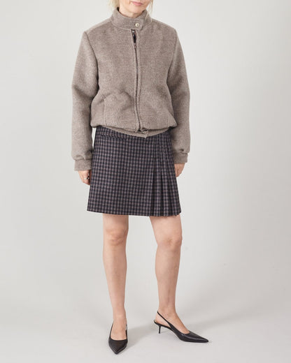 Person wearing a gray jacket and plaid skirt on a white background