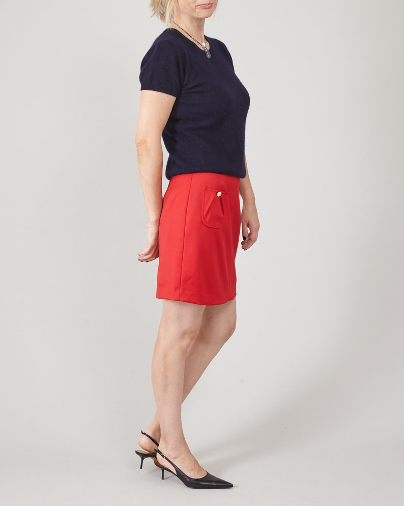 Person wearing a navy top and red mini skirt in studio
