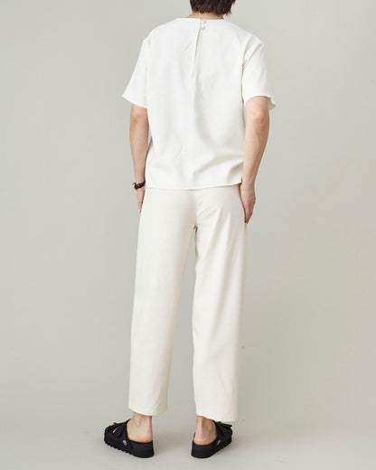 Back view of handmade ivory raw silk tapered trousers with clean cropped hem, worn with matching boxy top and black platform sandals, by Fine Thee
