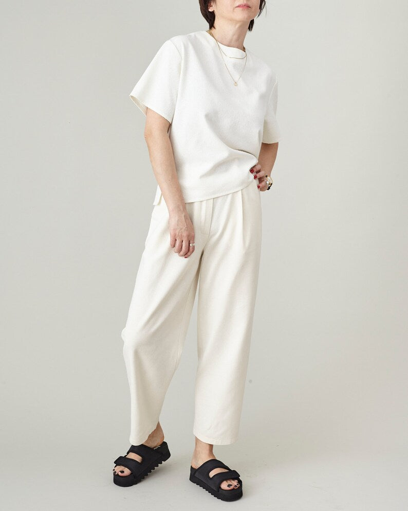 Woman wearing a matching ivory raw silk set — handmade tapered pleated trousers and boxy short-sleeve top — styled with black platform sandals, by Fine Thee