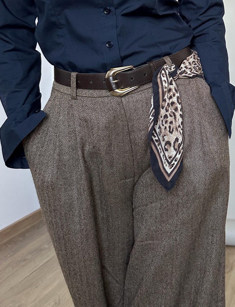 Person wearing a navy shirt, brown pants, and a leopard print scarf with a belt.