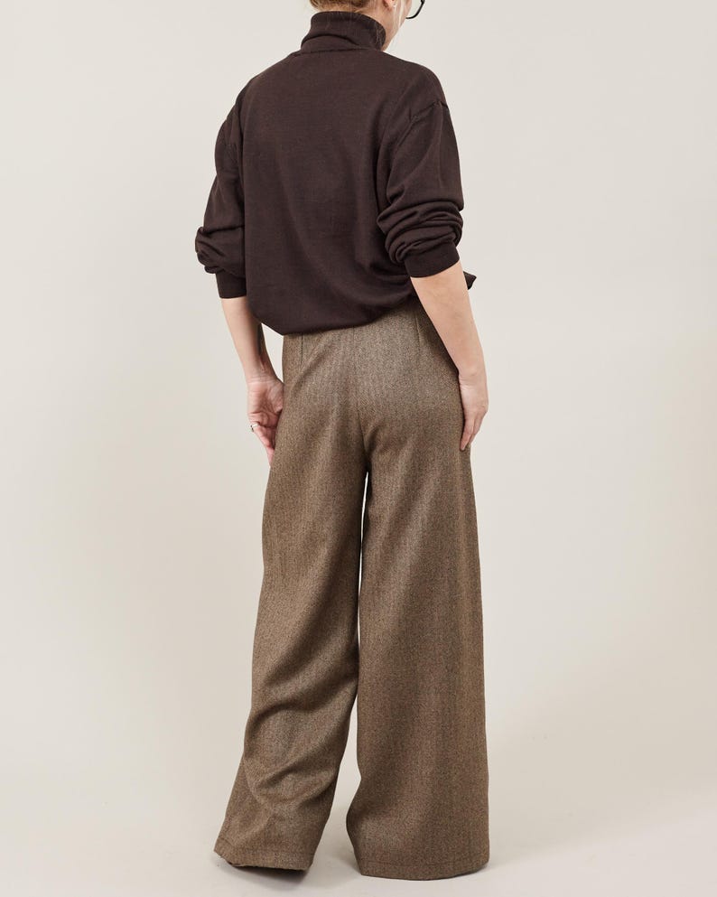 Person wearing a brown sweater and wide-leg brown pants on a plain background