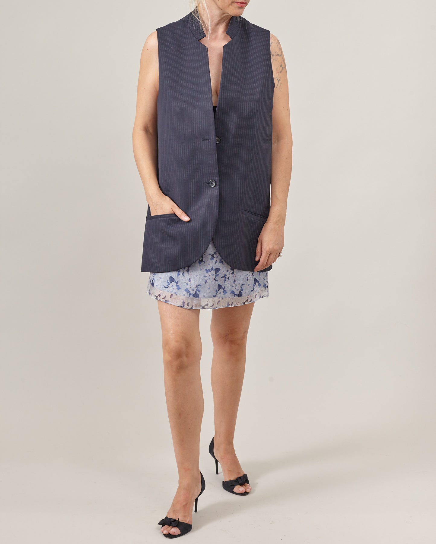 women wearing a navy pinstripe sleeveless blazer and a floral blue mini skirt
