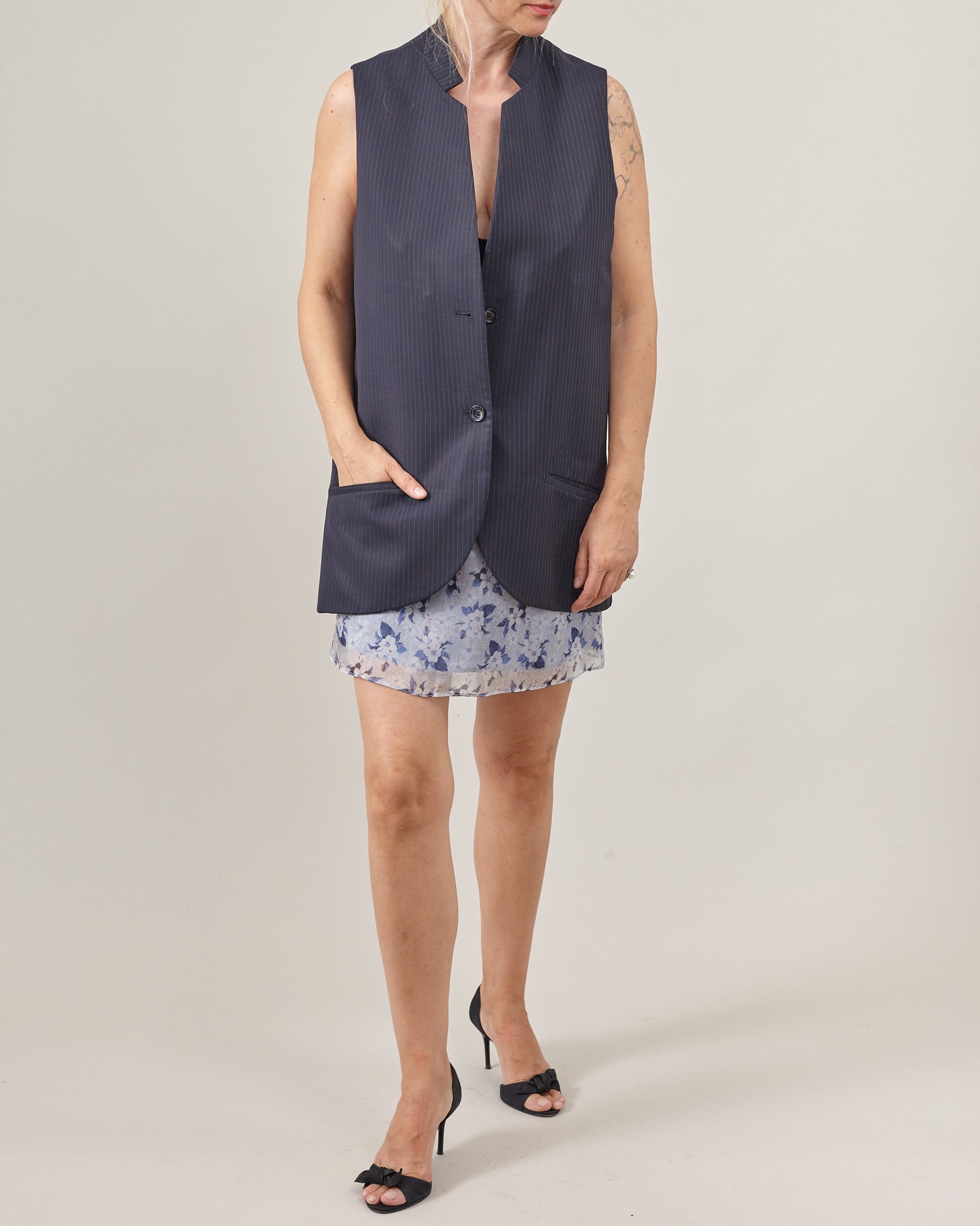women wearing a navy pinstripe sleeveless blazer and a floral blue mini skirt