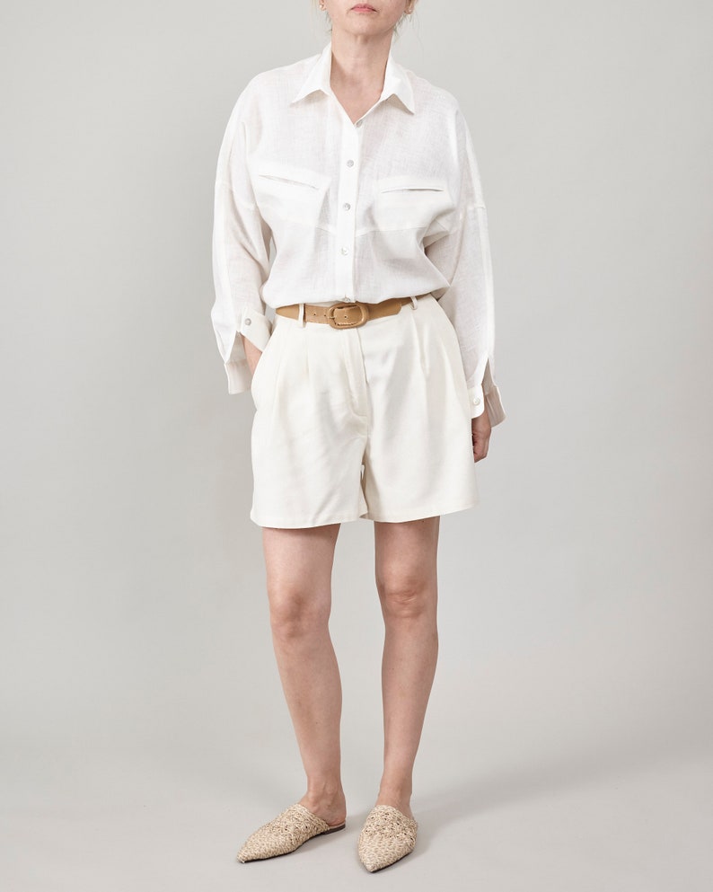 women wearing an all white resort outfit with oversized linen blouse and pleated high waist shorts