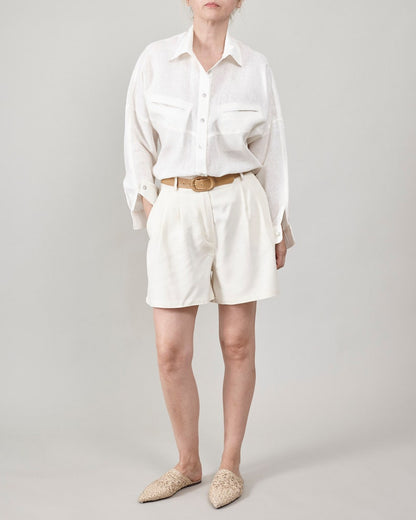 women wearing an all white resort outfit with oversized linen blouse and pleated high waist shorts
