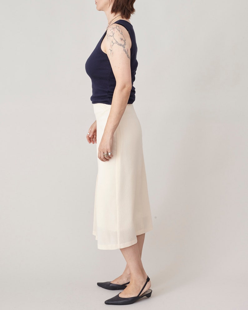 Person wearing a navy top and white skirt on a plain background