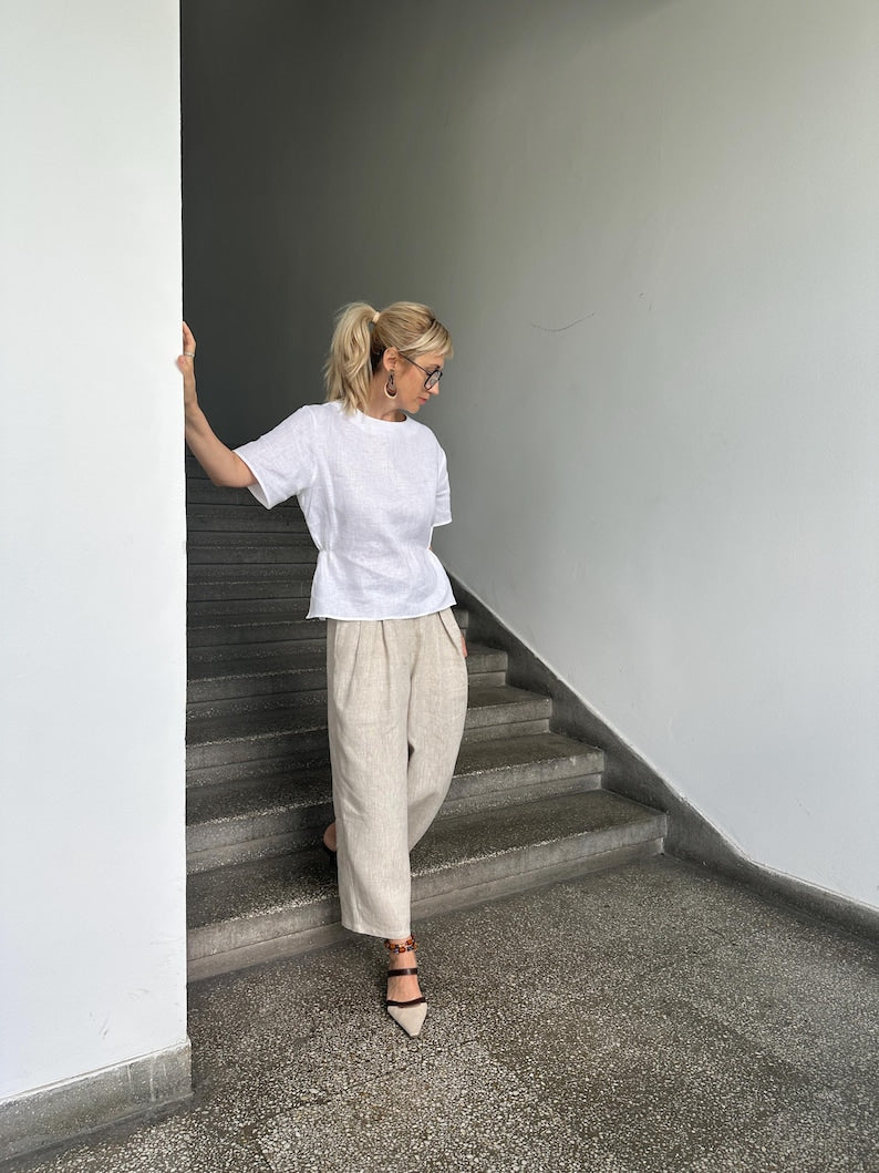 Woman in a white shirt and beige pants standing on a staircase.
