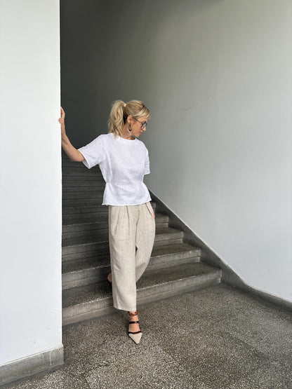 Woman in a white shirt and beige pants standing on a staircase.