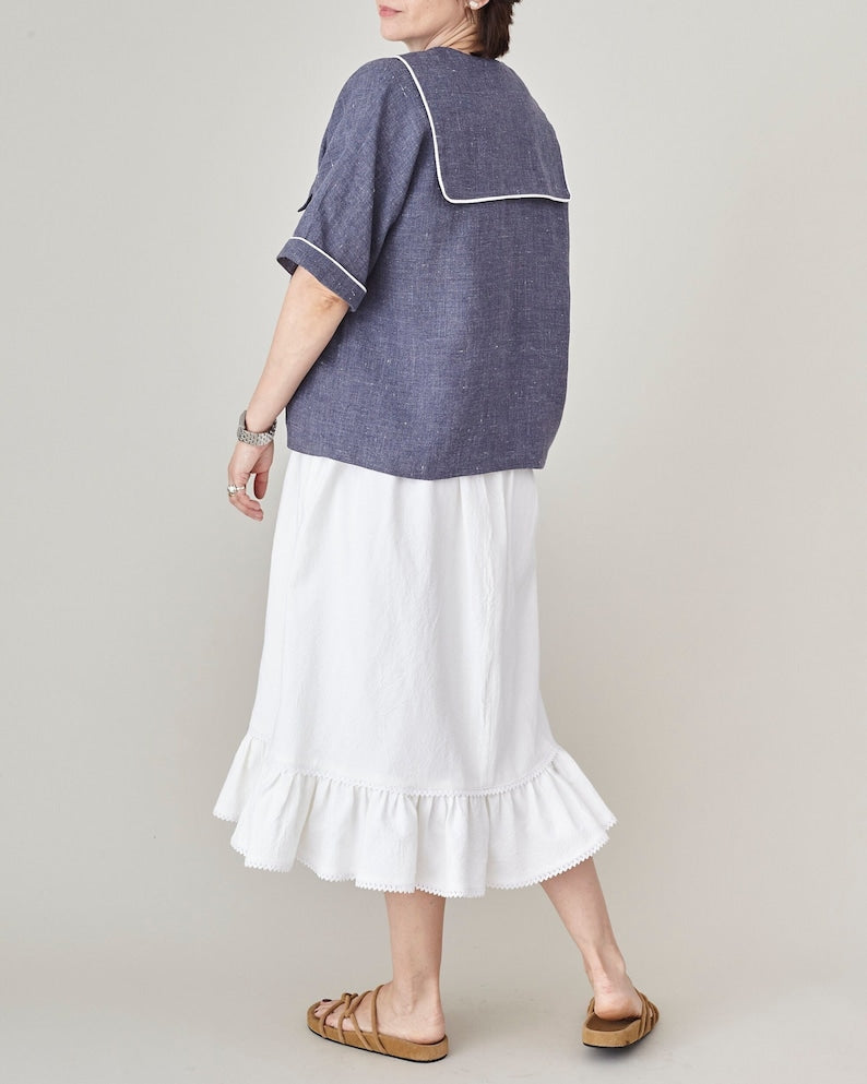 Person wearing a blue top and white skirt on a plain background