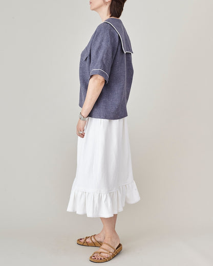 Person wearing a blue top and white skirt on a plain background
