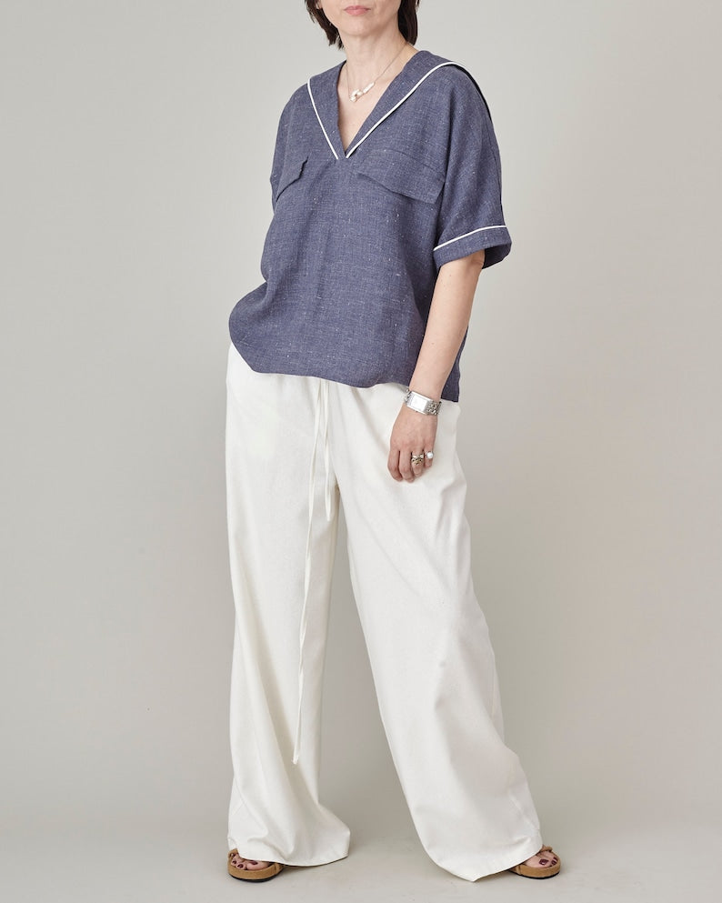Person wearing a blue shirt and white pants on a plain background