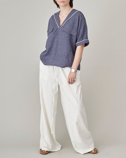 Person wearing a blue shirt and white pants on a plain background