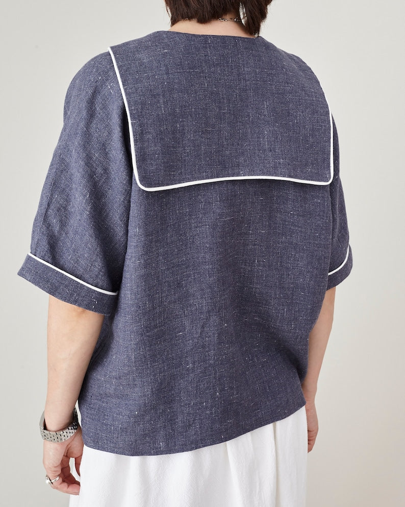 Person wearing a blue shirt with white trim on a plain background