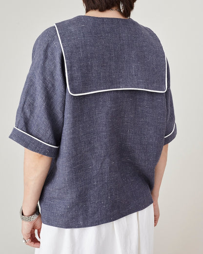 Person wearing a blue shirt with white trim on a plain background
