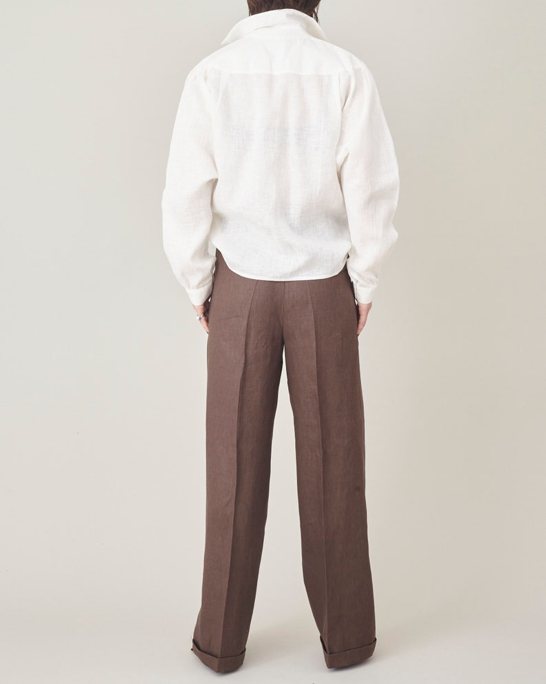 Person wearing a white shirt and brown pants on a plain background