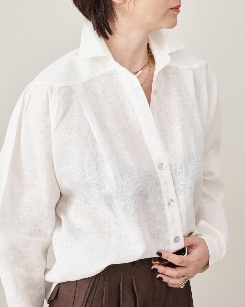 Person wearing a white button-up shirt with a neutral background