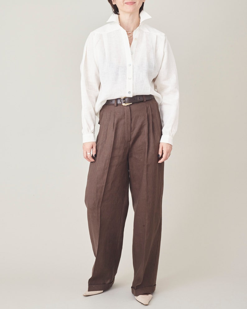 Person wearing a white shirt and brown pants on a plain background