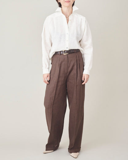 Person wearing a white shirt and brown pants on a plain background