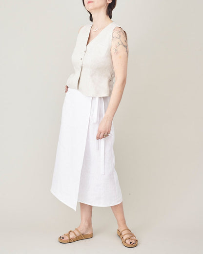 Person wearing a white sleeveless top and white pants on a plain background