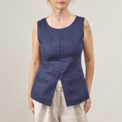 Woman wearing a blue sleeveless top against a plain background
