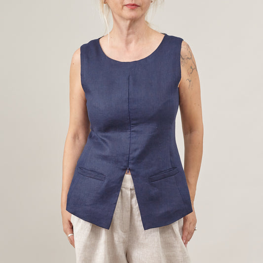Woman wearing a blue sleeveless top against a plain background