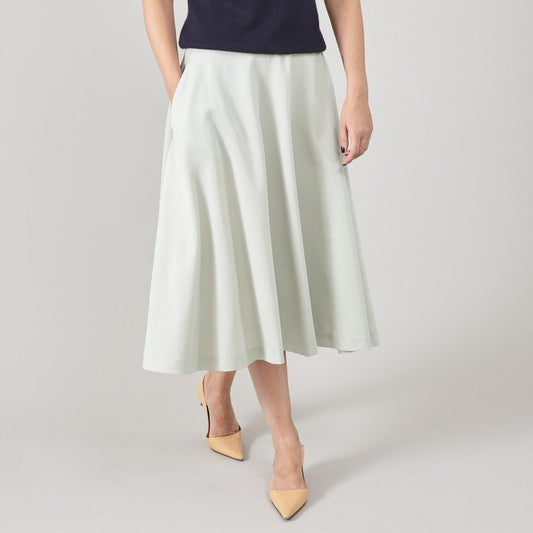 Person wearing a light green full midi skirt on a plain background
