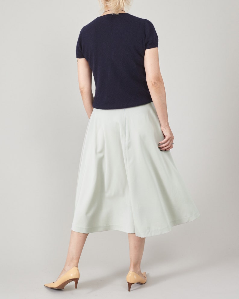 Person wearing a navy top and light-mint skirt on a plain background