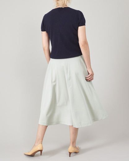 Person wearing a navy top and light-mint skirt on a plain background