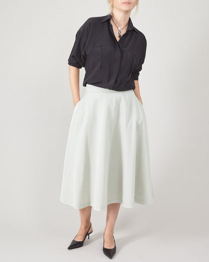 Person wearing a black shirt and mint skirt on a plain background