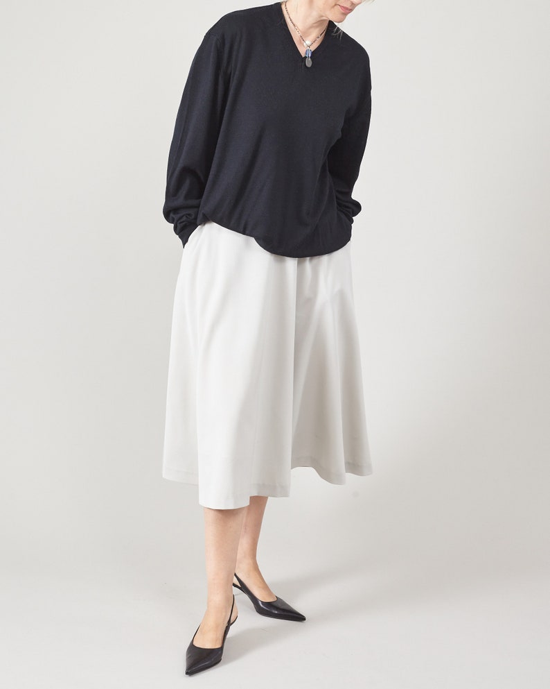 Person wearing a black oversized sweater and mint skirt on a plain background