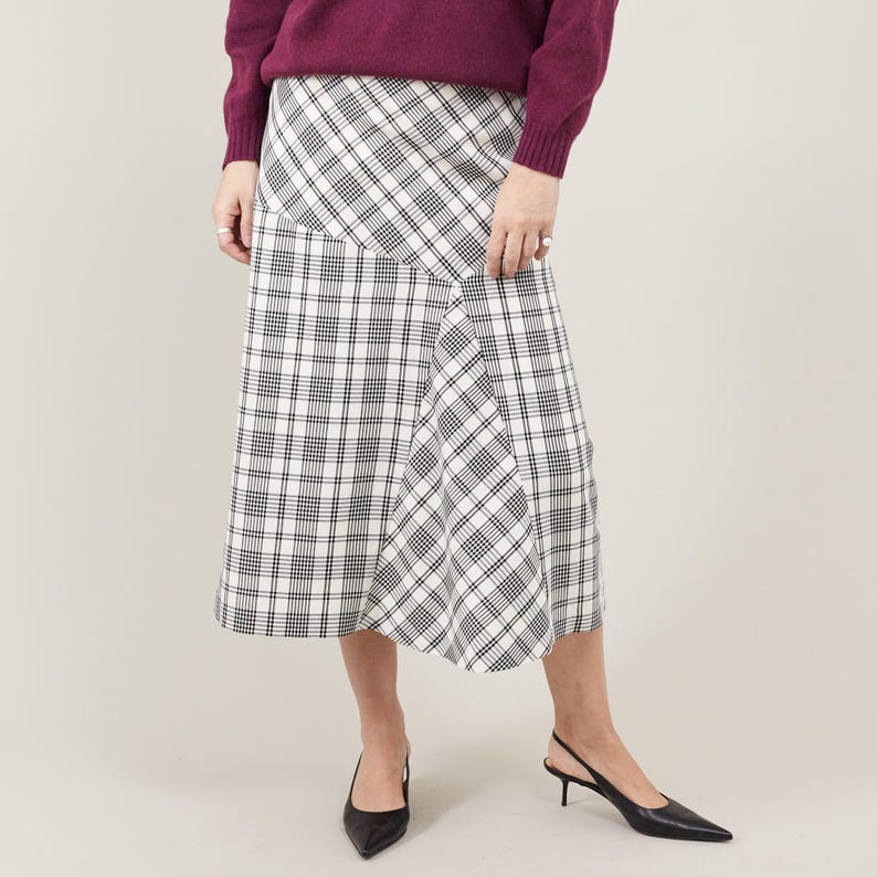 Person wearing a plaid skirt and purple sweater on a plain background